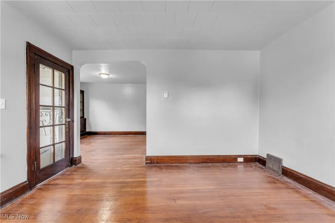 Empty room with arched walkways and light wood-type flooring