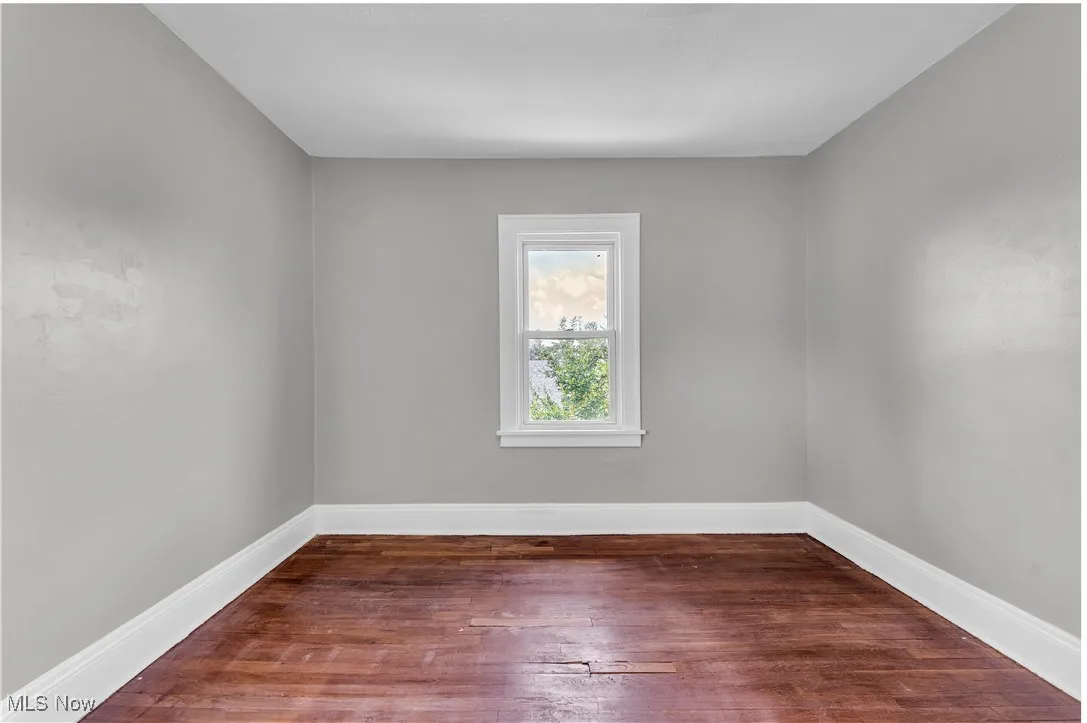 Spare room with dark wood-style flooring and baseboards