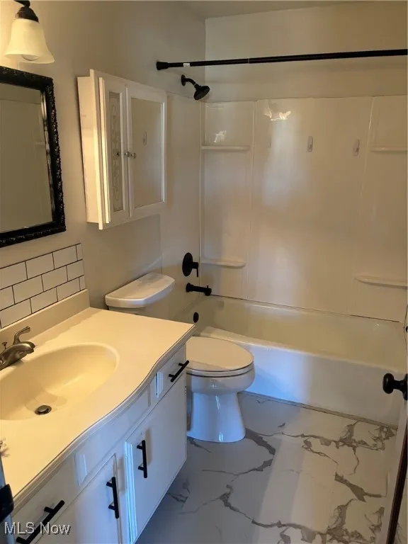Bathroom with vanity,  shower combination, and marble look flooring