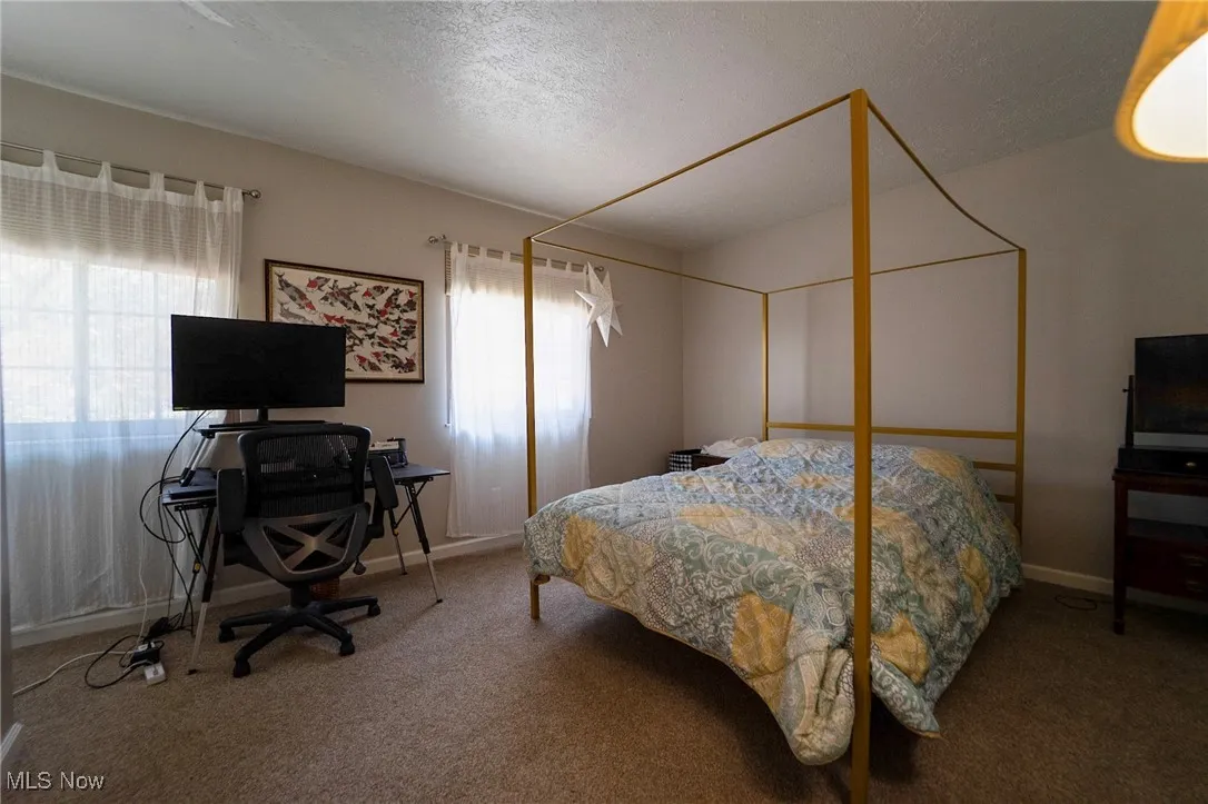 Carpeted bedroom with a textured ceiling and a desk
