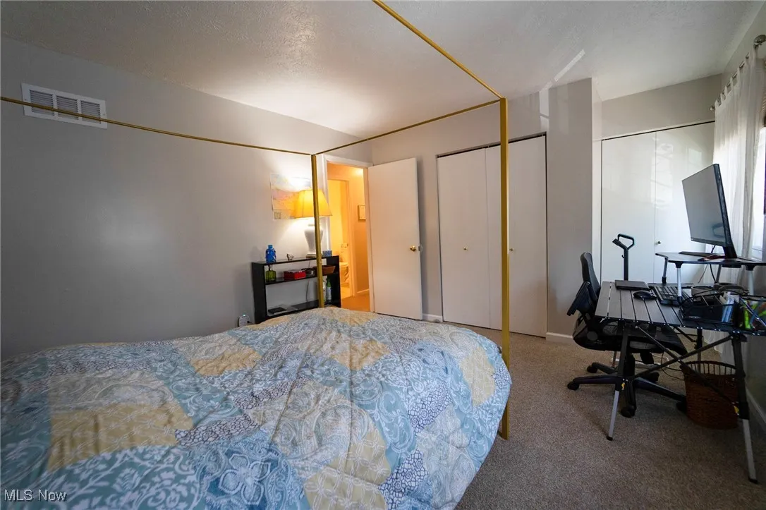 Bedroom featuring carpet floors, a closet, a desk, and a textured ceiling