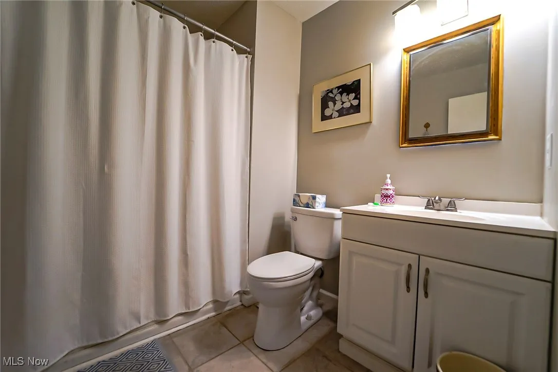 Bathroom with light tile patterned flooring, vanity, and shower / bath combination with curtain