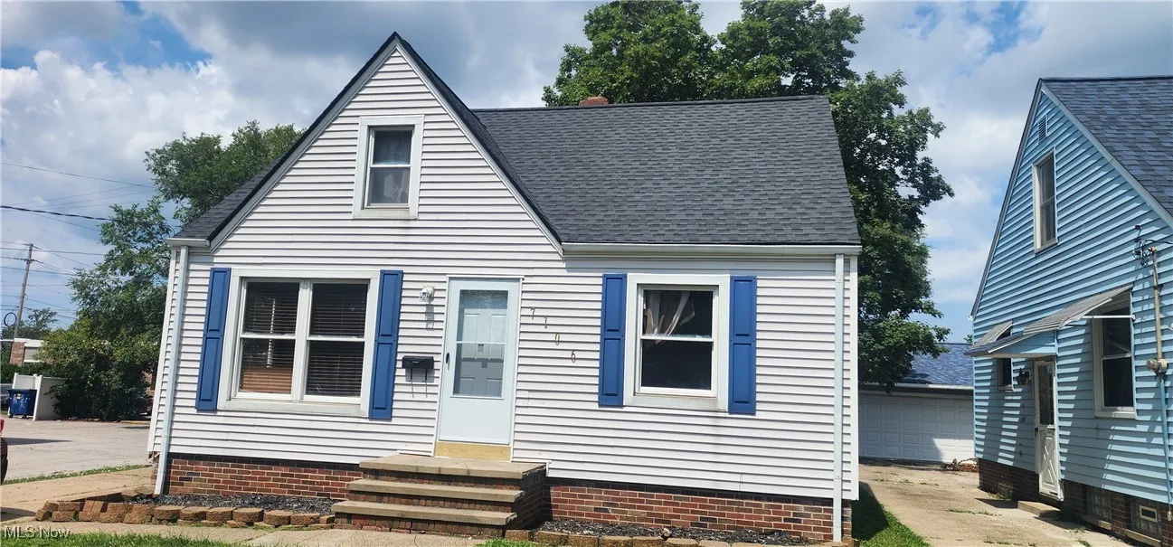 View of front of property with roof with shingles, an outdoor structure, and a garage