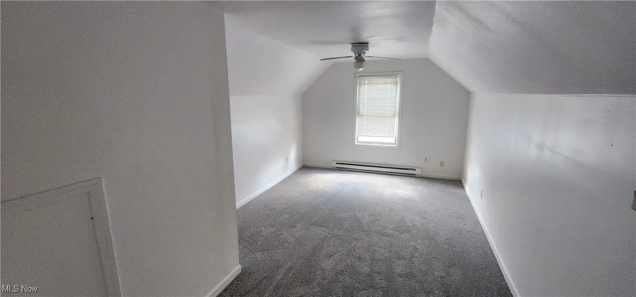 Bonus room featuring carpet, vaulted ceiling, a ceiling fan, a baseboard heating unit, and a textured ceiling