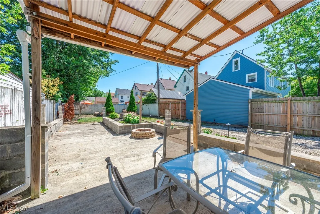 Fenced backyard featuring outdoor dining space, a patio, a residential view, and a fire pit