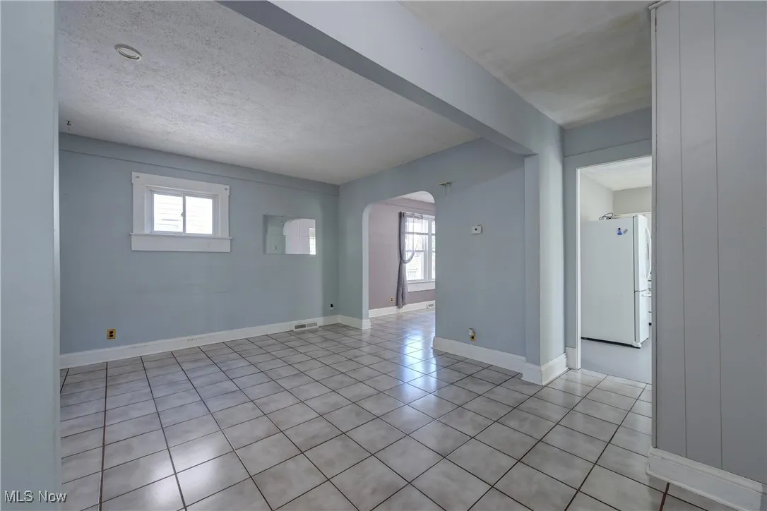 Spare room with arched walkways, light tile patterned floors, and a textured ceiling