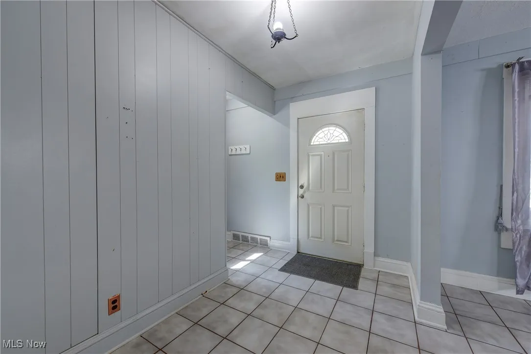 Foyer entrance featuring wood walls and light tile patterned floors