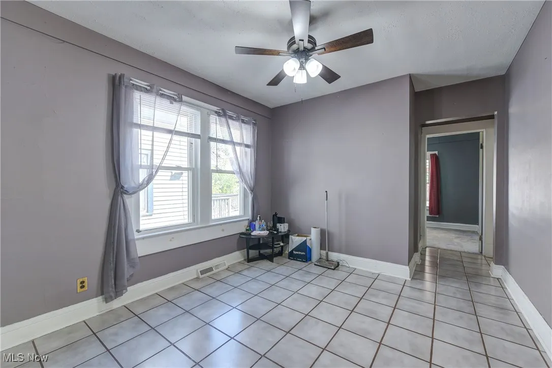 Unfurnished room with light tile patterned floors and a ceiling fan