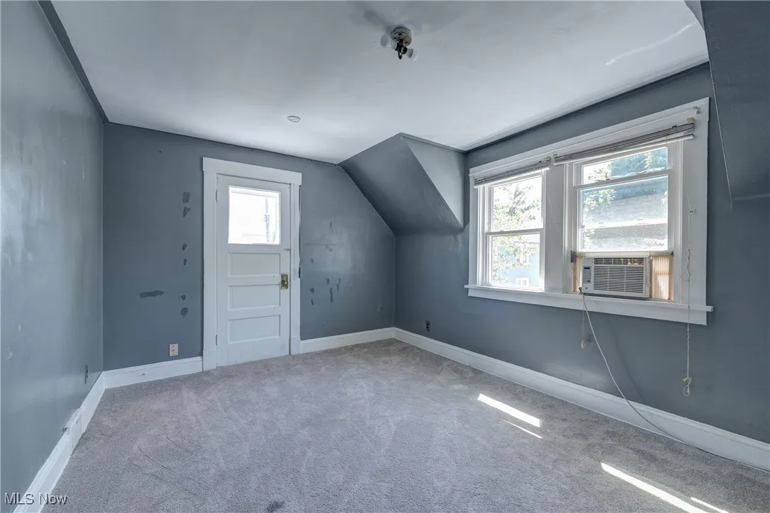 Additional living space featuring carpet flooring and cooling unit
