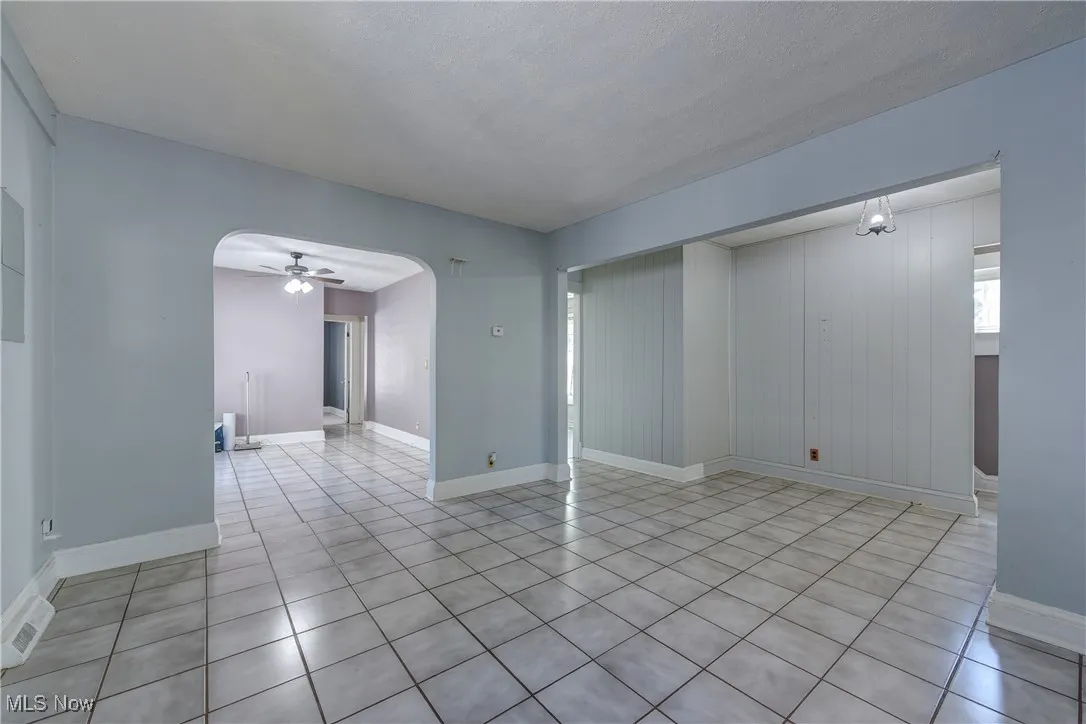 Unfurnished room featuring ceiling fan, light tile patterned flooring, and arched walkways