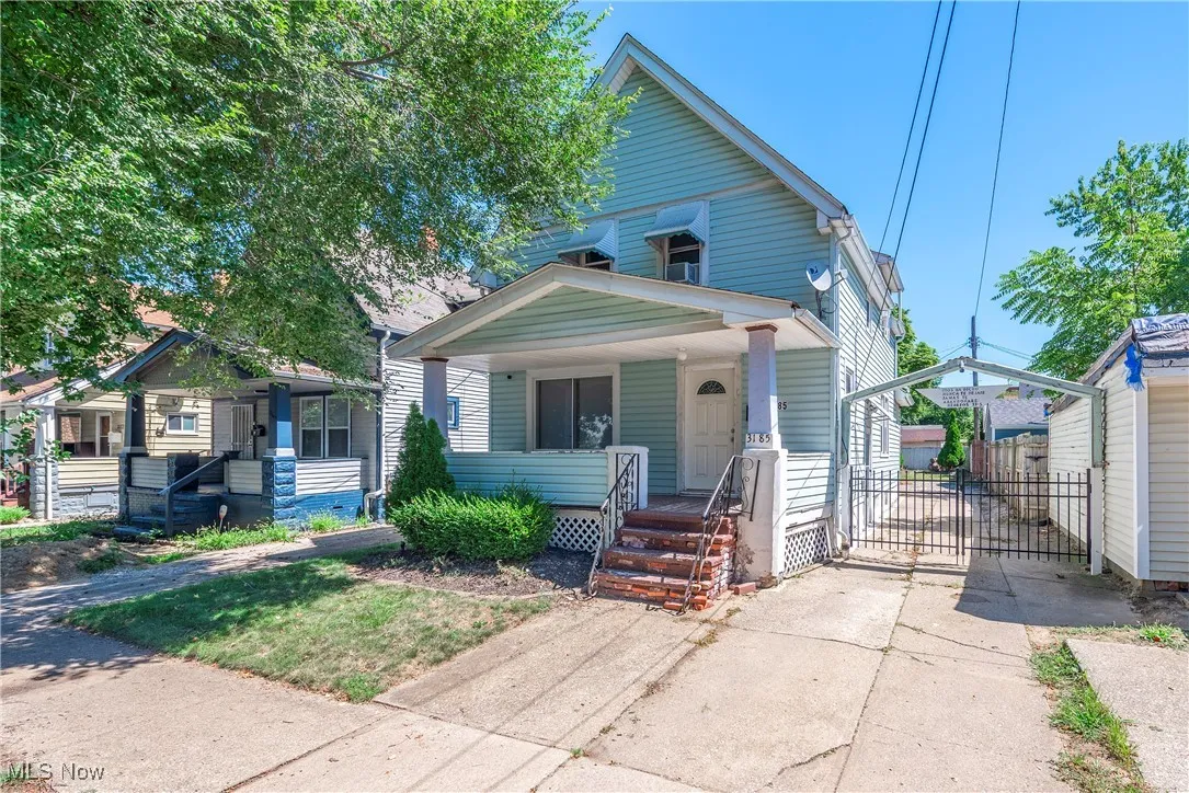 View of front of home with covered porch, a gate, and driveway