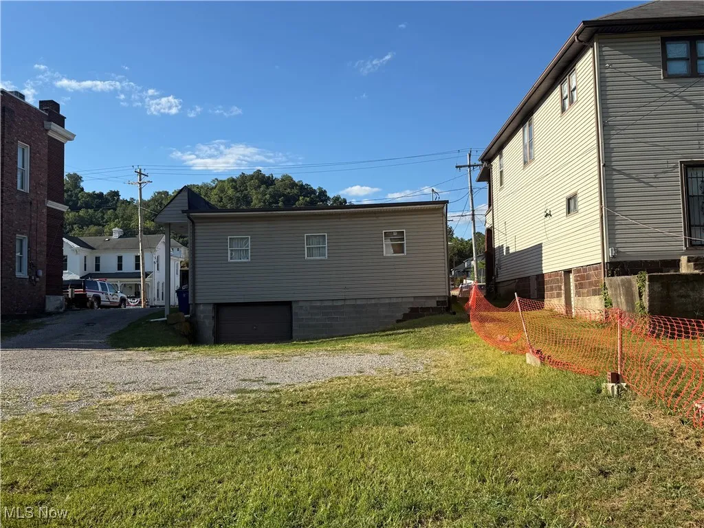 View of property exterior with an attached garage, driveway, and a yard