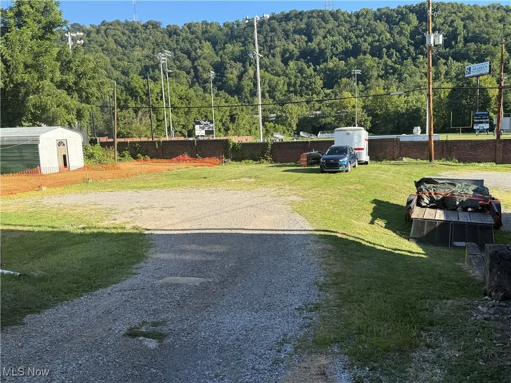 Surrounding community with a forest view, a yard, and a storage shed