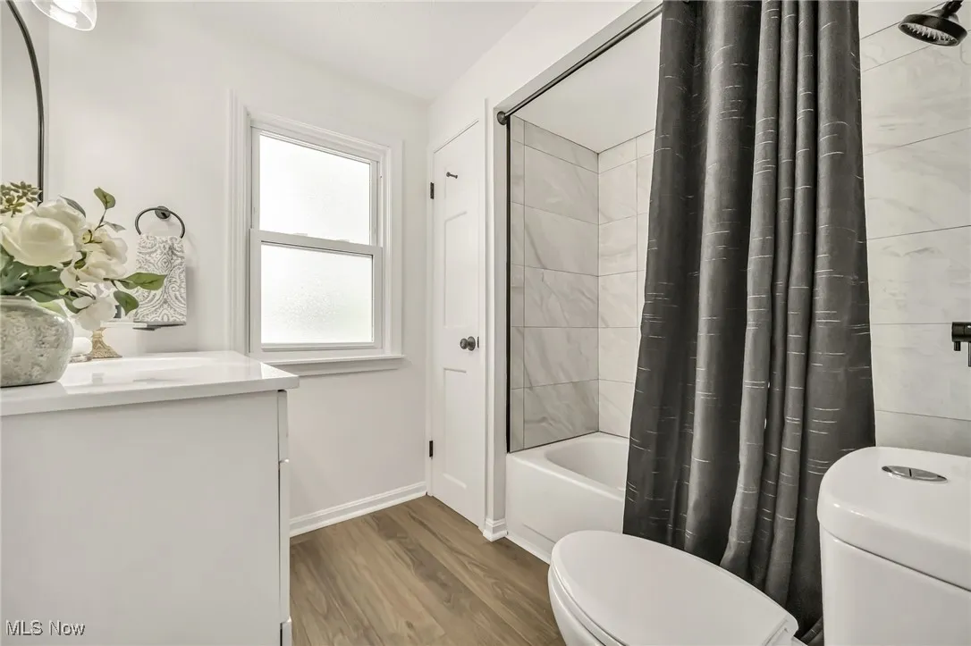 Full bath with vanity, shower / bathtub combination with curtain, and wood finished floors
