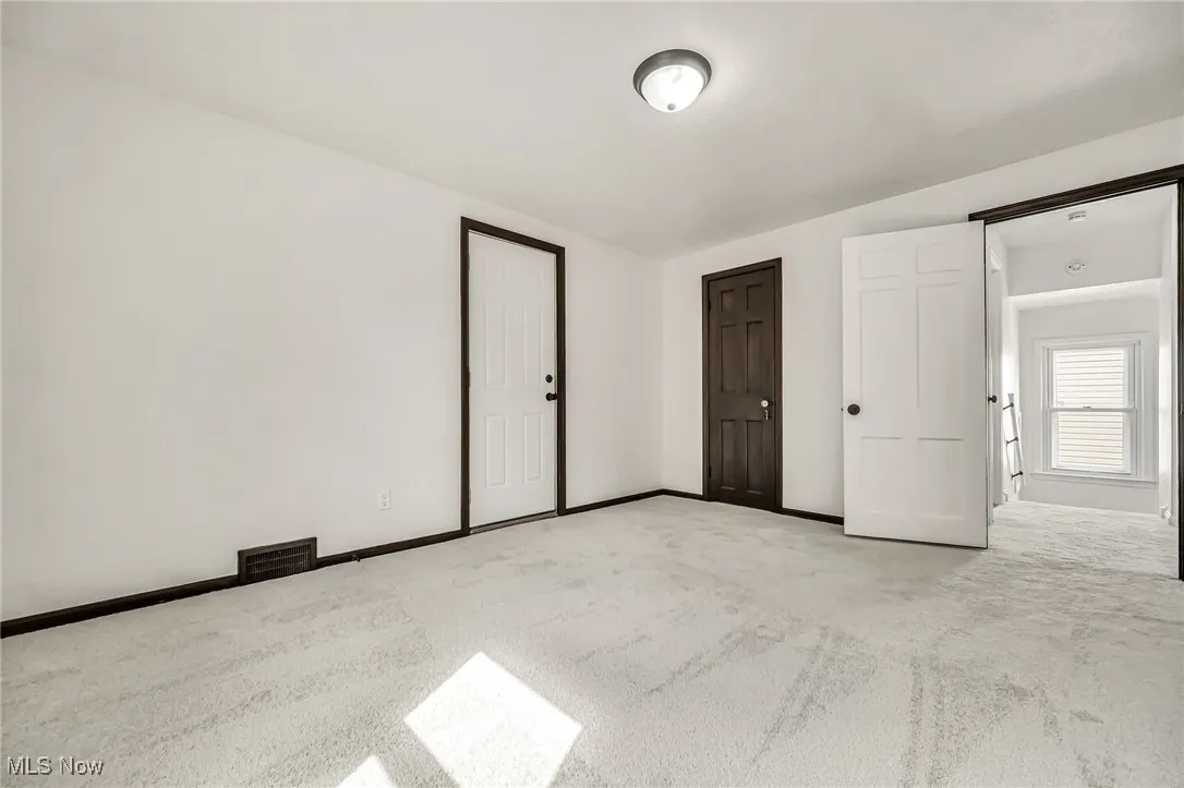 Unfurnished bedroom featuring light colored carpet and baseboards