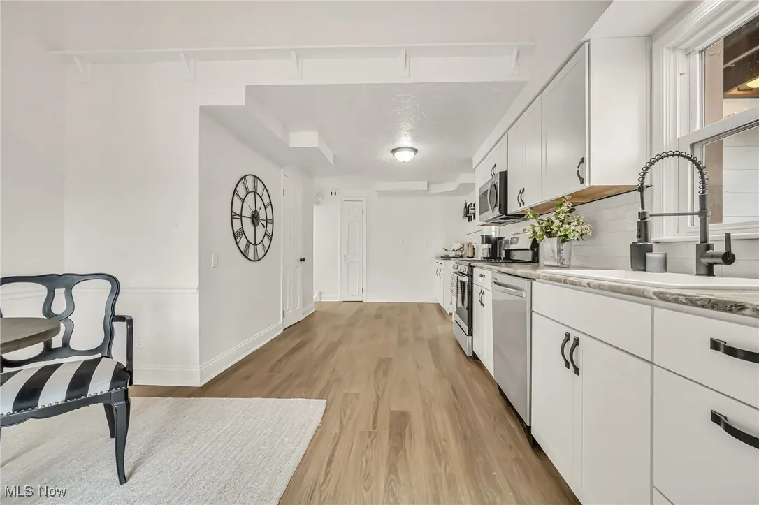 Kitchen featuring white cabinetry, light wood finished floors, stainless steel appliances, and tasteful backsplash