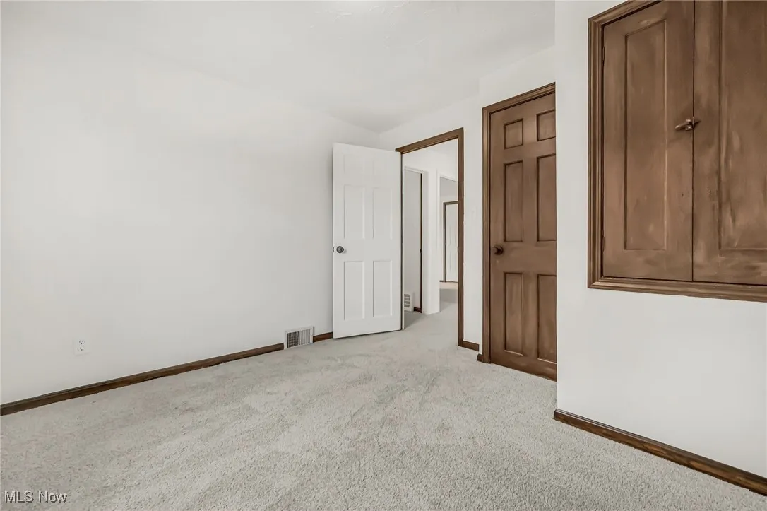 Empty room featuring baseboards and light carpet