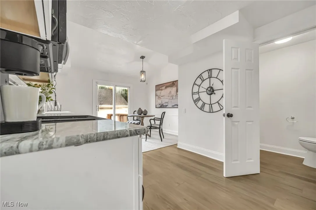 Kitchen featuring light wood-style floors, pendant lighting, and light stone countertops