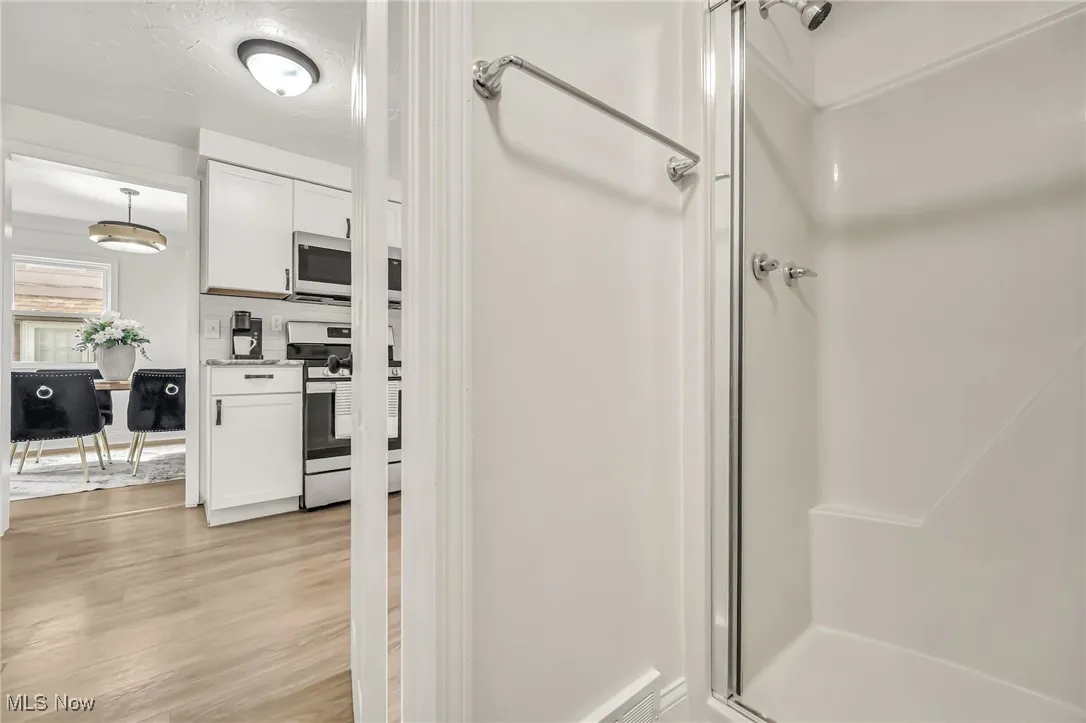 Full bathroom with a shower stall and light wood-type flooring