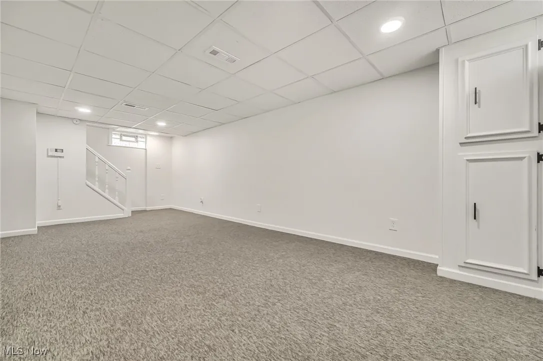 Finished below grade area featuring carpet, recessed lighting, a paneled ceiling, and stairs