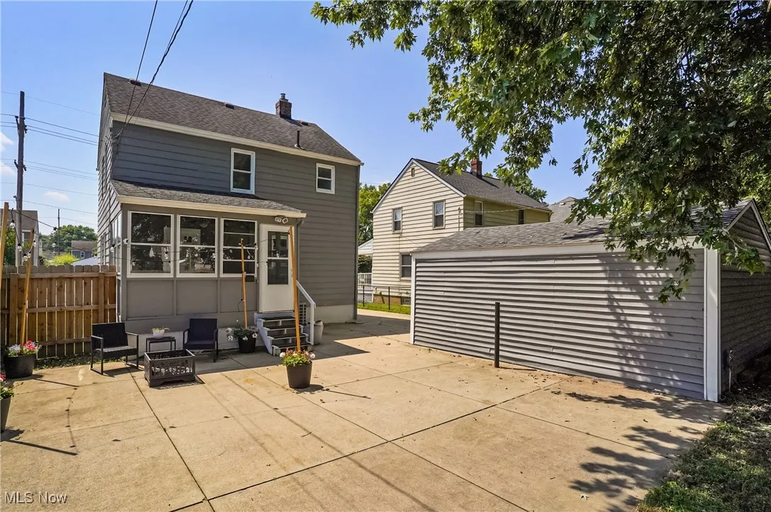 Rear view of property featuring a patio, a chimney, roof with shingles, and a sunroom