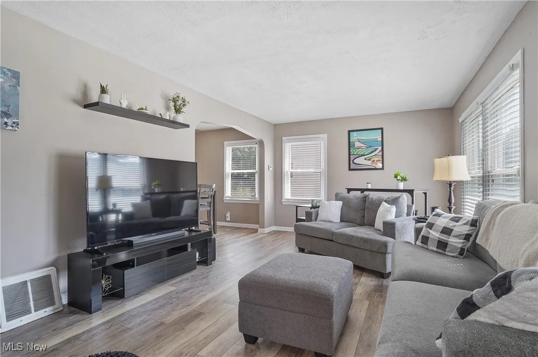 Living area with arched walkways, light wood finished floors, and a textured ceiling