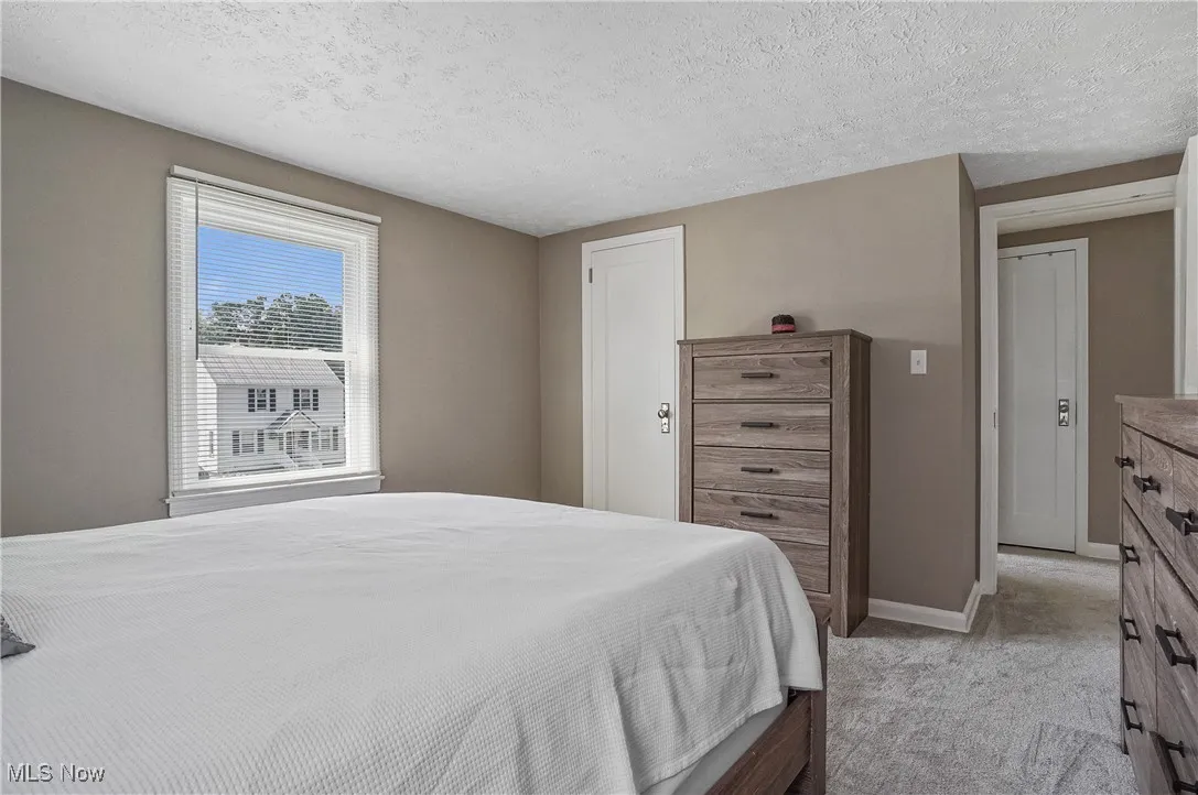 Bedroom with a textured ceiling, light carpet, and a closet