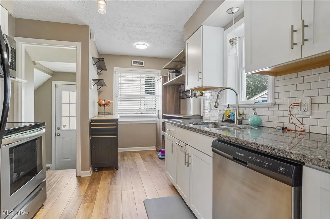 Kitchen with white cabinetry, stainless steel appliances, light wood-style floors, and a textured ceiling