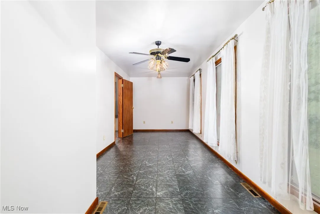 Empty room featuring baseboards and a ceiling fan