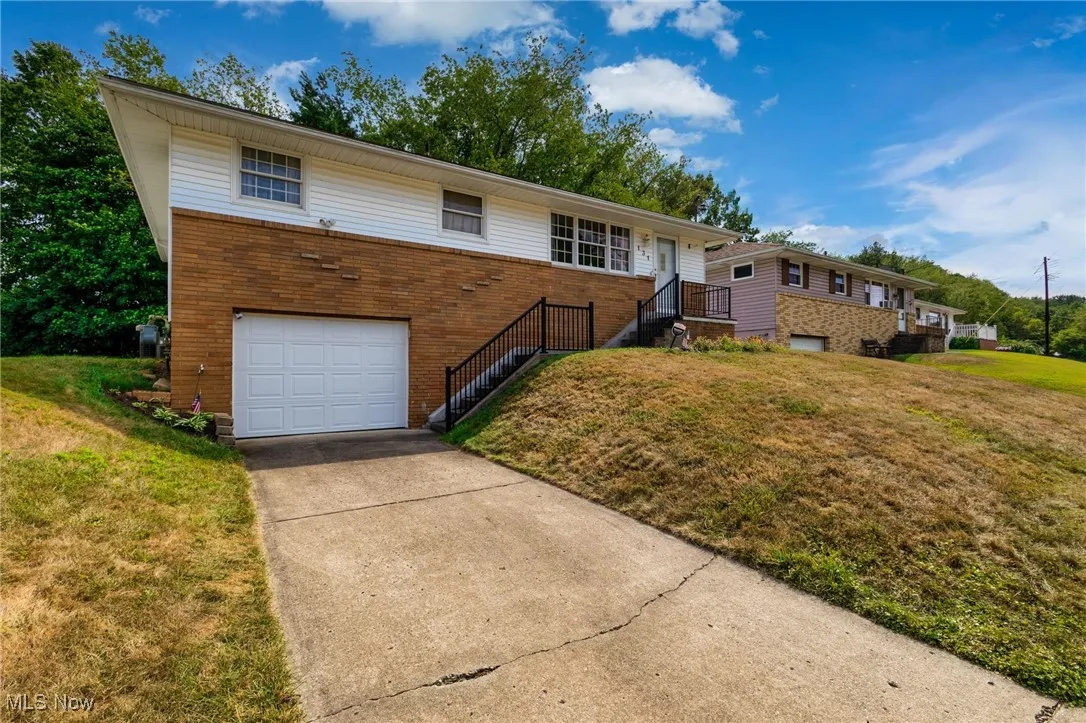 View of front of property with an attached garage, brick siding, driveway, and a front yard