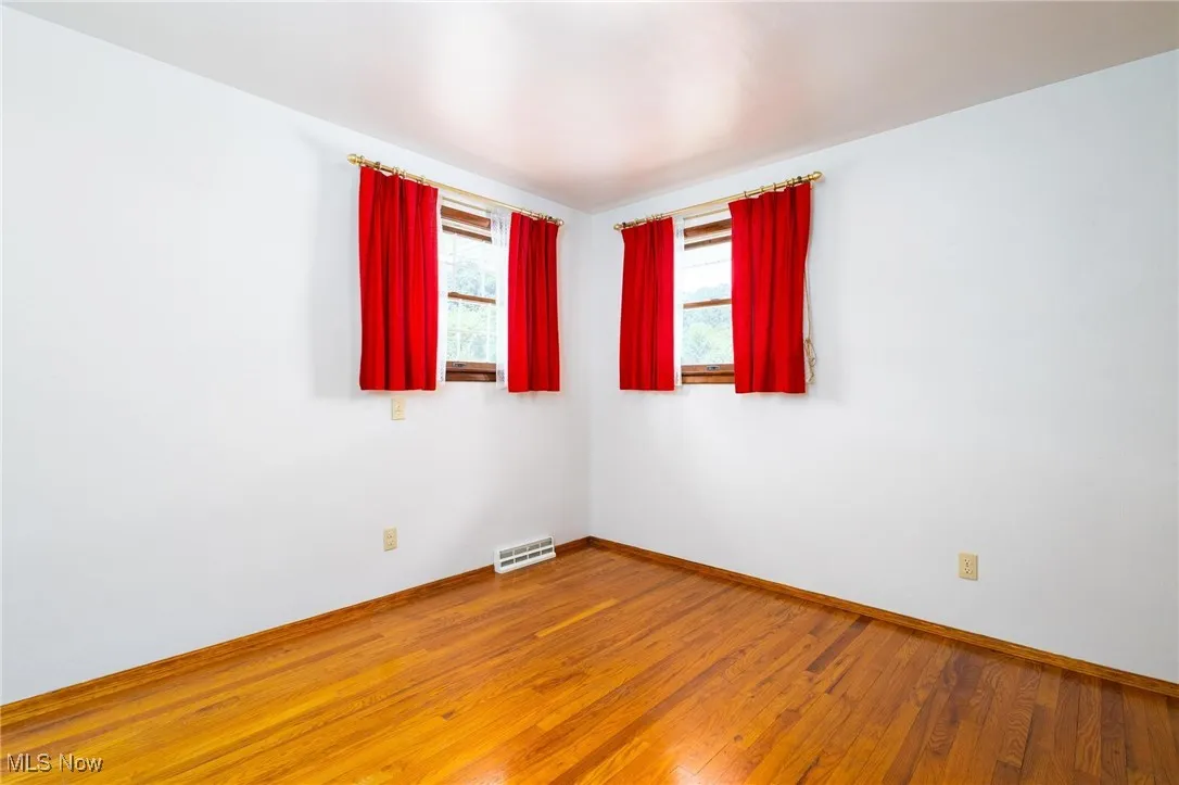 Unfurnished room featuring hardwood / wood-style floors and baseboards