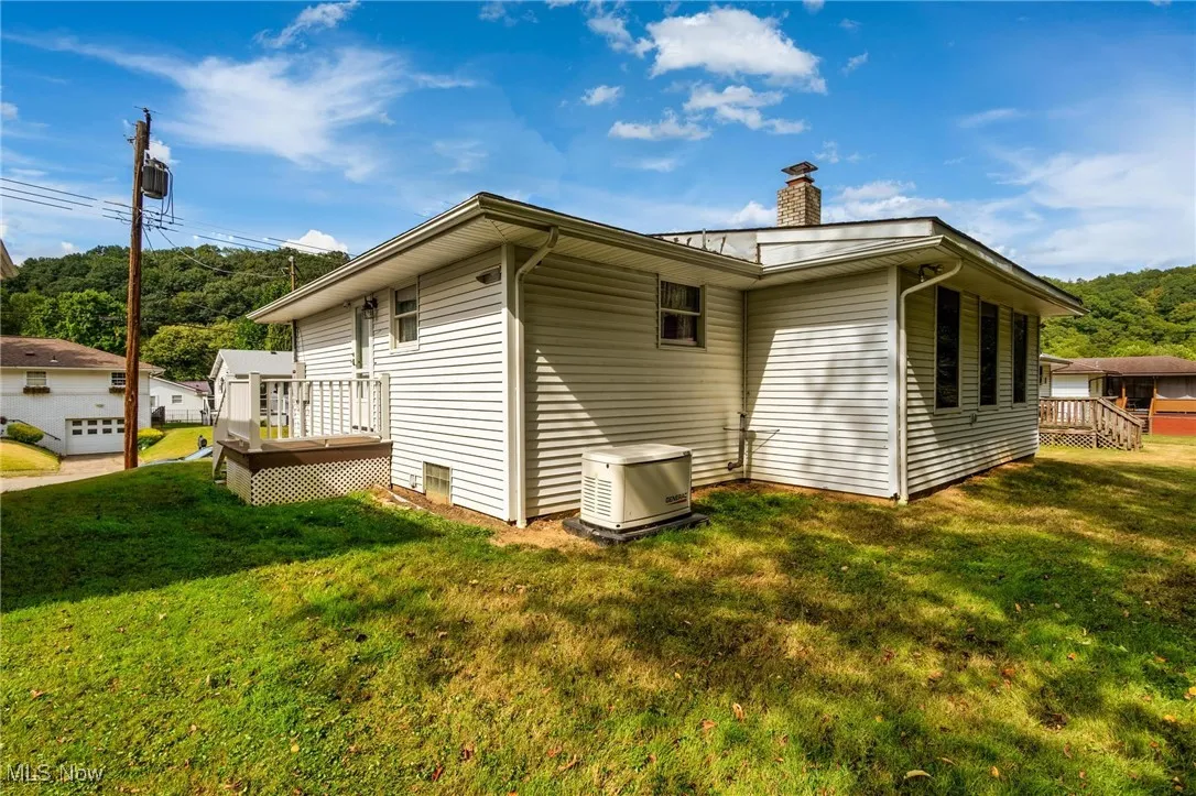 View of home's exterior featuring a yard, a chimney, and a deck