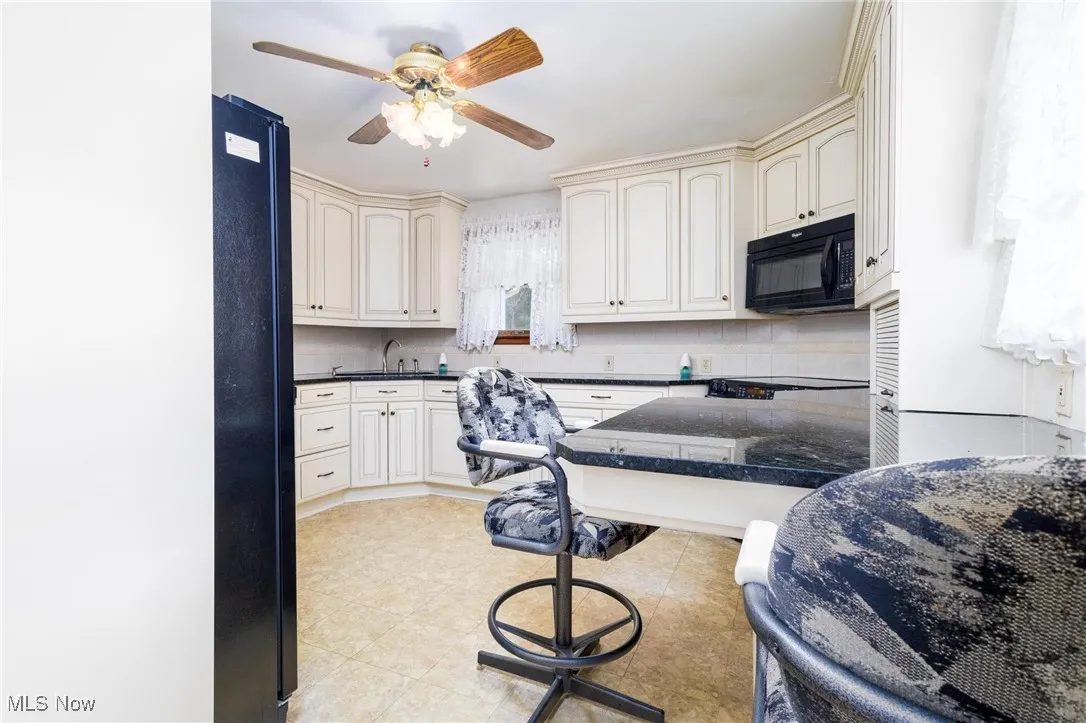Kitchen with black appliances, tasteful backsplash, ceiling fan, and cream cabinetry