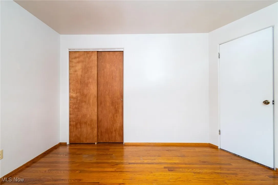 Unfurnished bedroom with wood finished floors and a closet