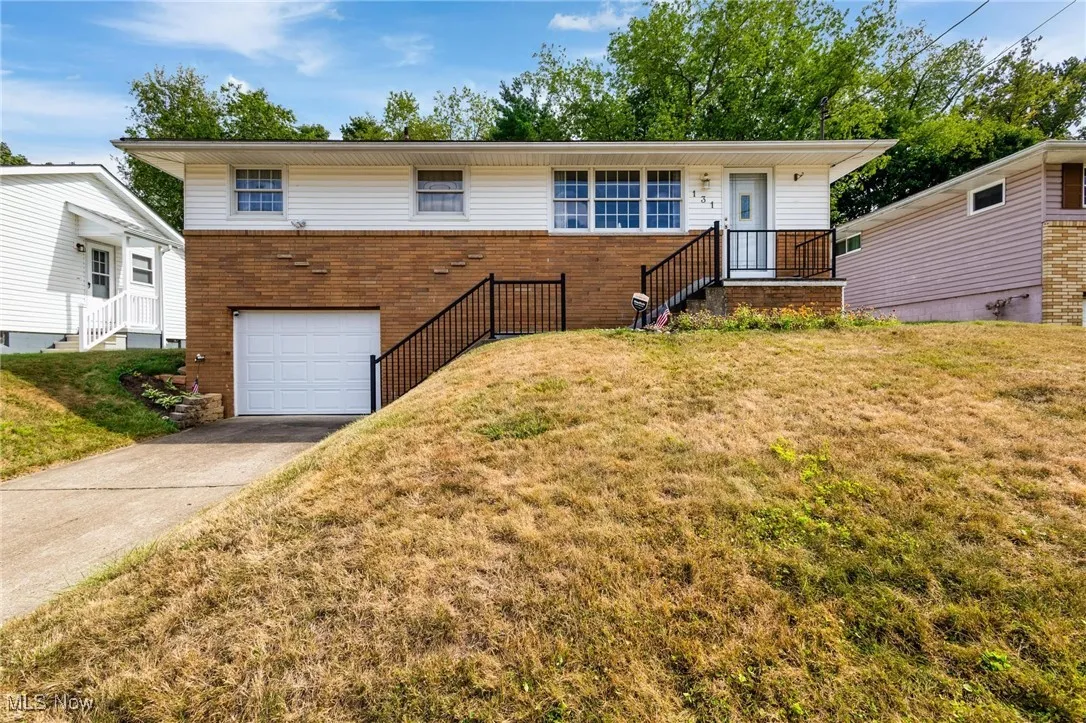 View of front of home with brick siding, a garage, a front lawn, and concrete driveway
