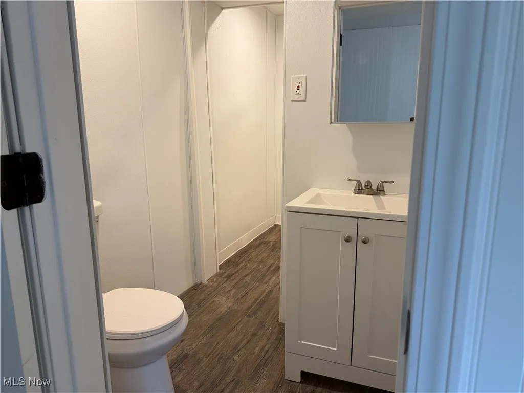 Half bath with vanity and dark wood-style floors