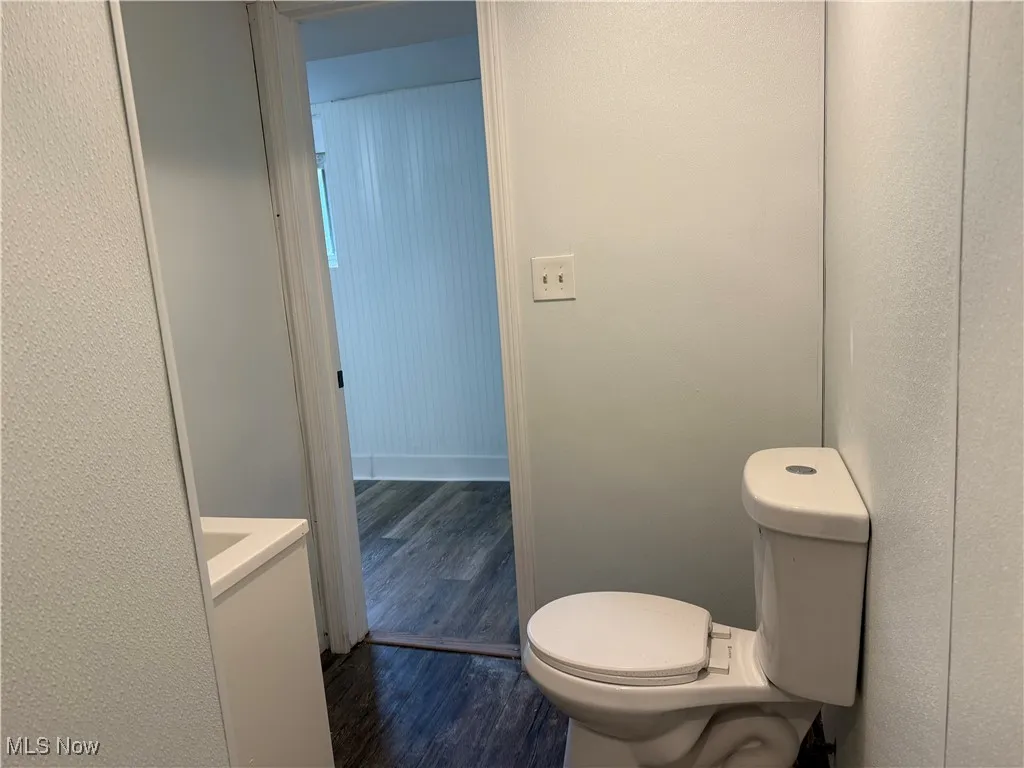 Half bathroom with dark wood-style floors and vanity