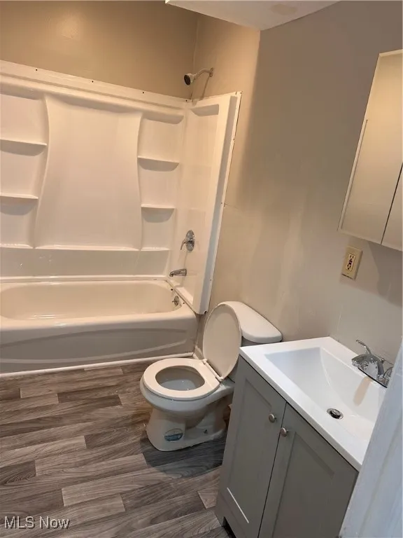Bathroom with shower / bathtub combination, vanity, and dark wood-style flooring