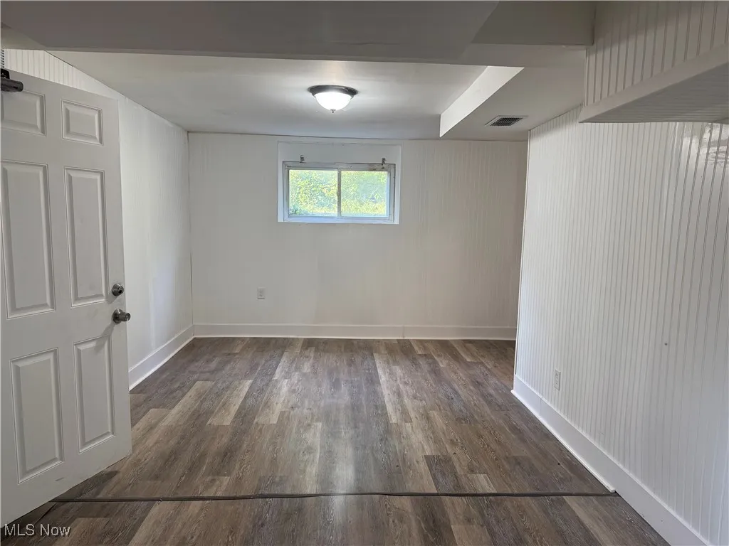 Empty room with dark wood-style floors and baseboards