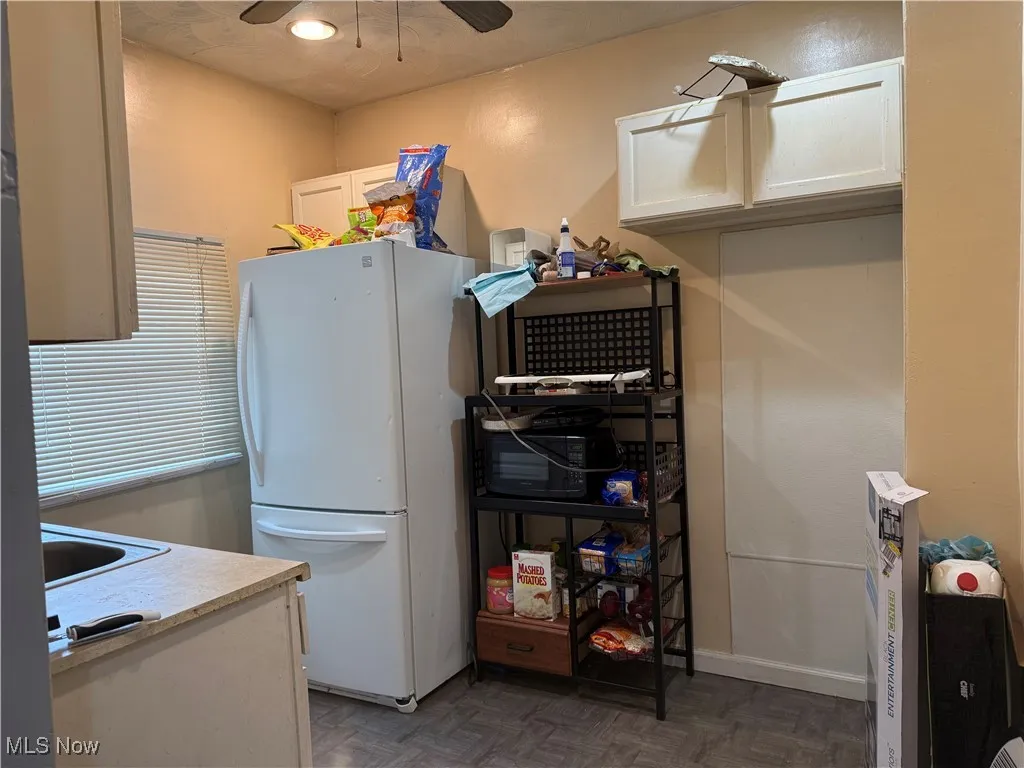 Kitchen featuring white cabinets, freestanding refrigerator, light countertops, and a ceiling fan