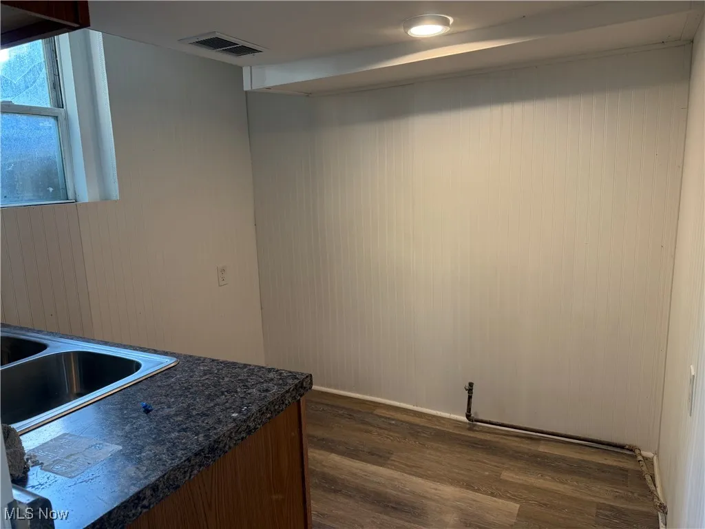 Kitchen featuring dark wood finished floors, wooden walls, and dark countertops