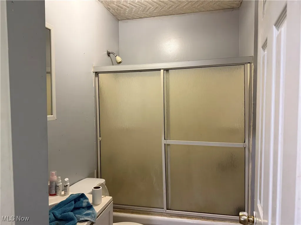 Bathroom featuring combined bath / shower with glass door and vanity