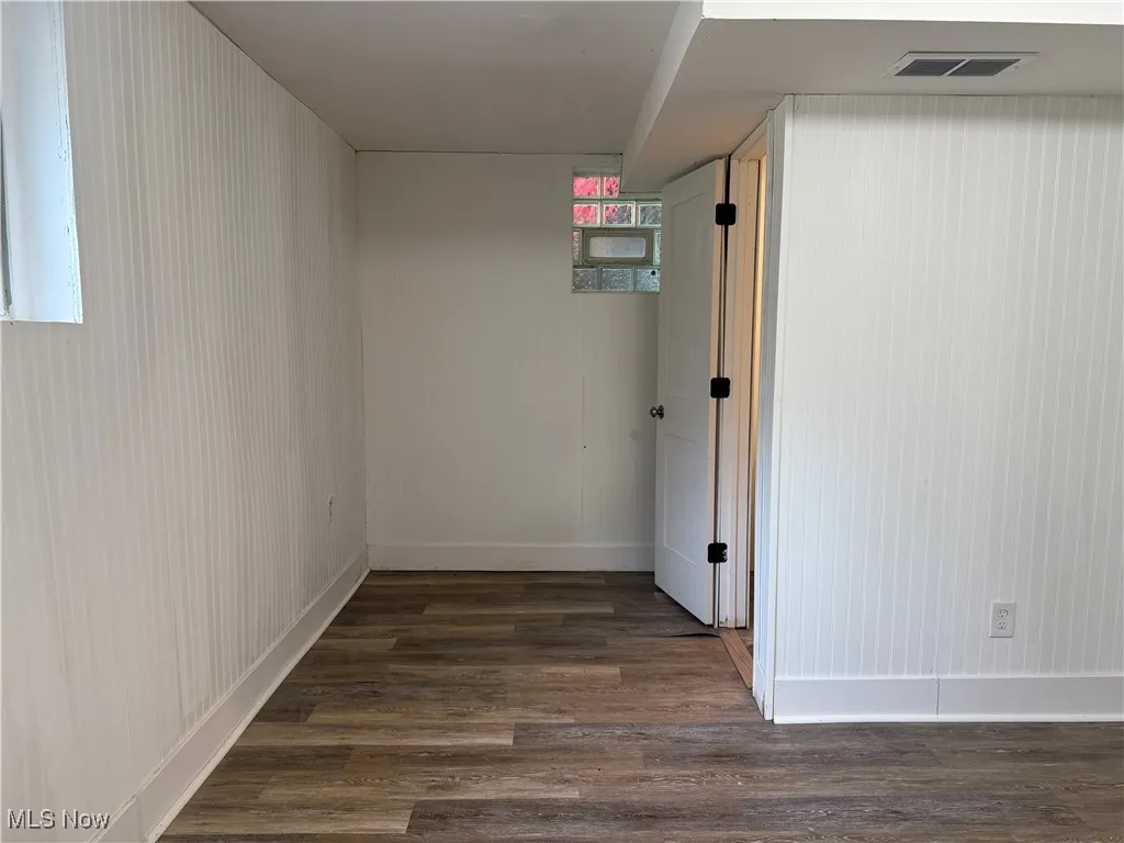 Hallway featuring dark wood-style floors and baseboards