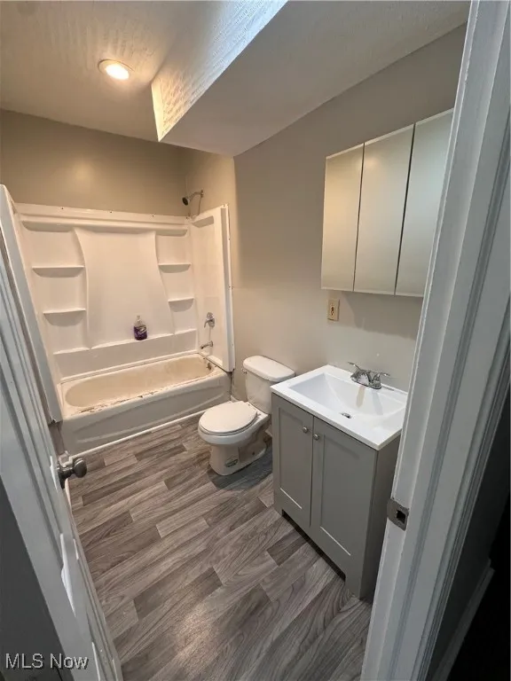 Bathroom with tub / shower combination, vanity, dark wood-style flooring, recessed lighting, and a textured ceiling