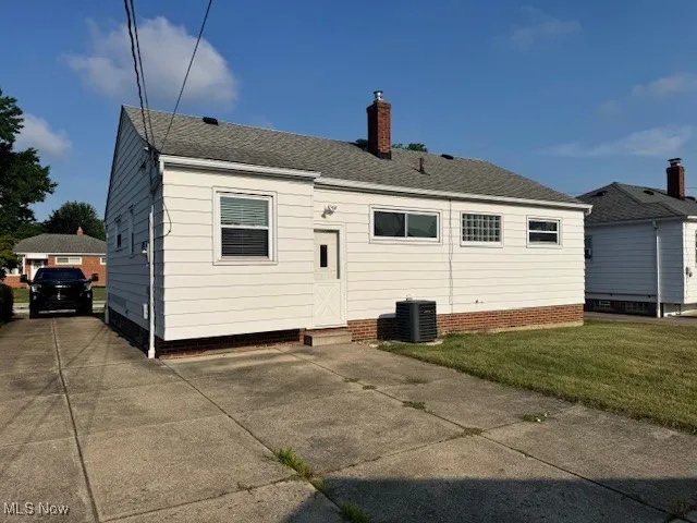 Rear view of property with a chimney, roof with shingles, and a yard