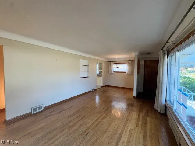 Unfurnished living room with wood finished floors and a chandelier