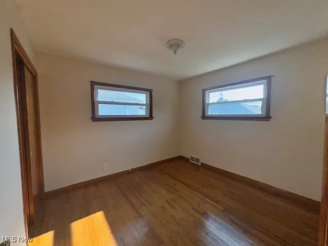 Unfurnished bedroom with wood finished floors and baseboards