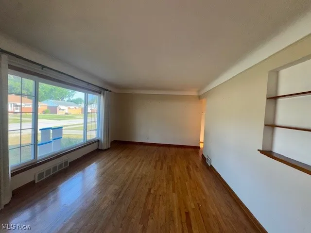 Empty room with dark wood-style floors and baseboards