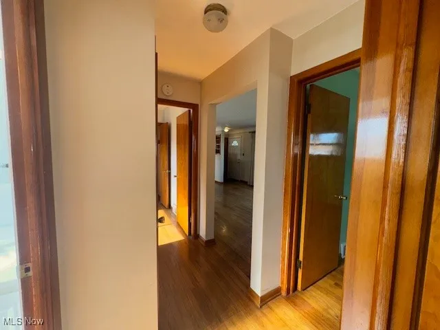 Corridor with light wood-style flooring and baseboards