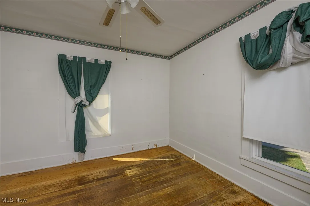 Unfurnished room with dark wood-style floors and ceiling fan